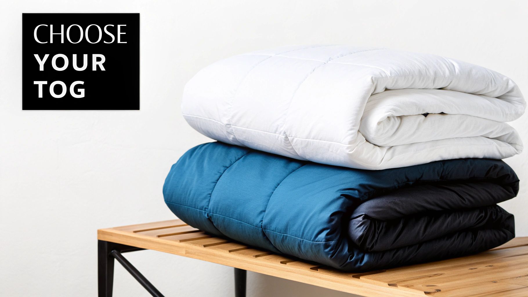 Stack of white, blue and black duvets with pillow on wooden bench showcasing tog rating options