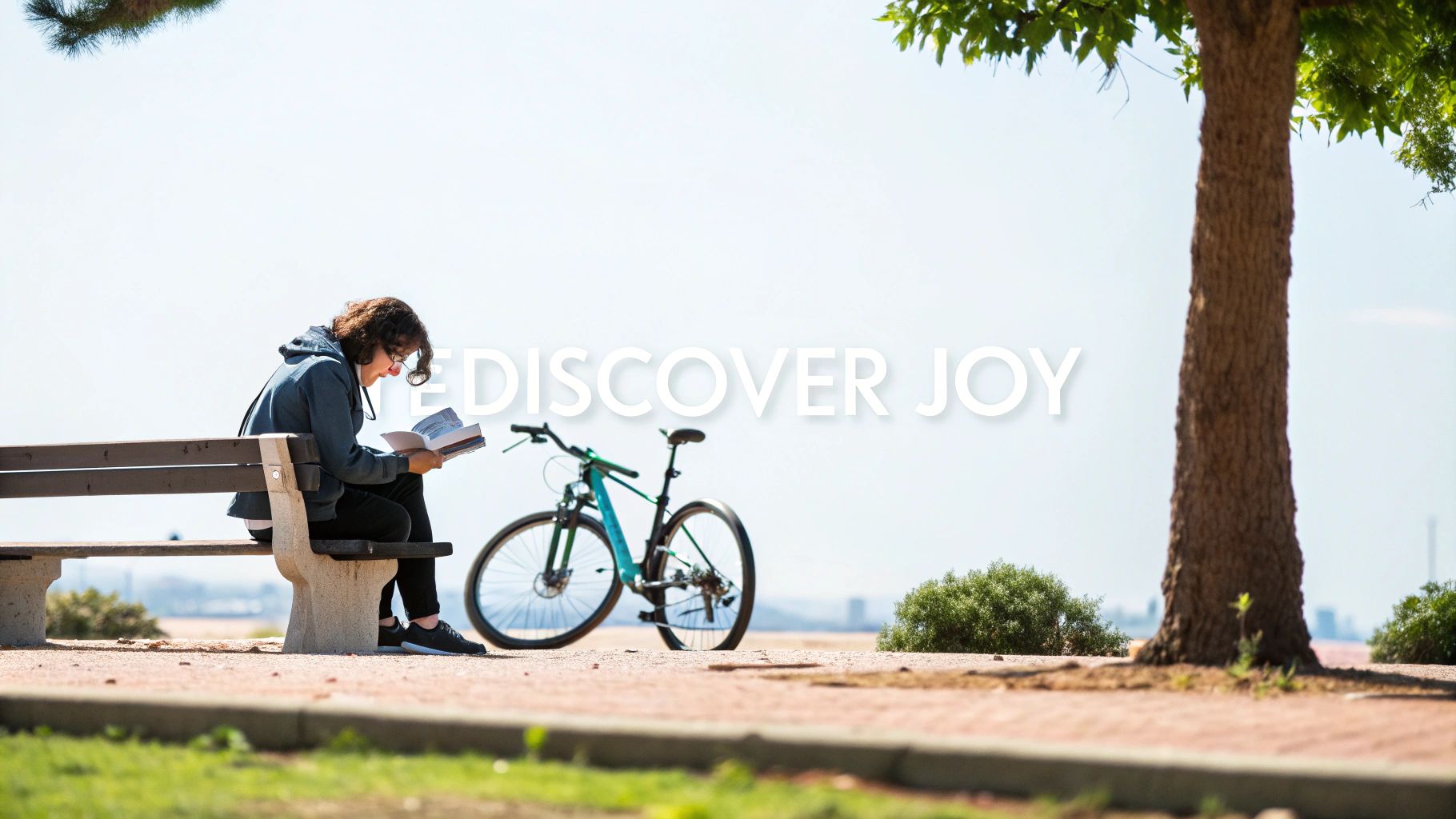 A person with glasses reads a book on a park bench, with a bicycle nearby and a tree.