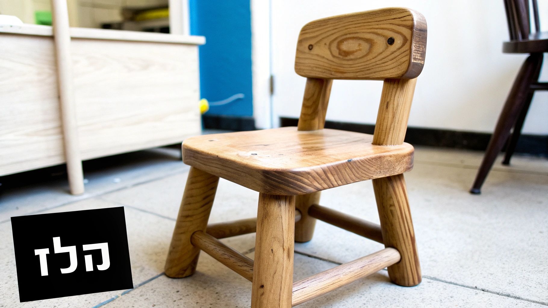 כיסא עץ מעוצב לילדים בצבע טבעי, מונח על רצפה בהירה עם כיתוב 'הלד' על שלט שחור.