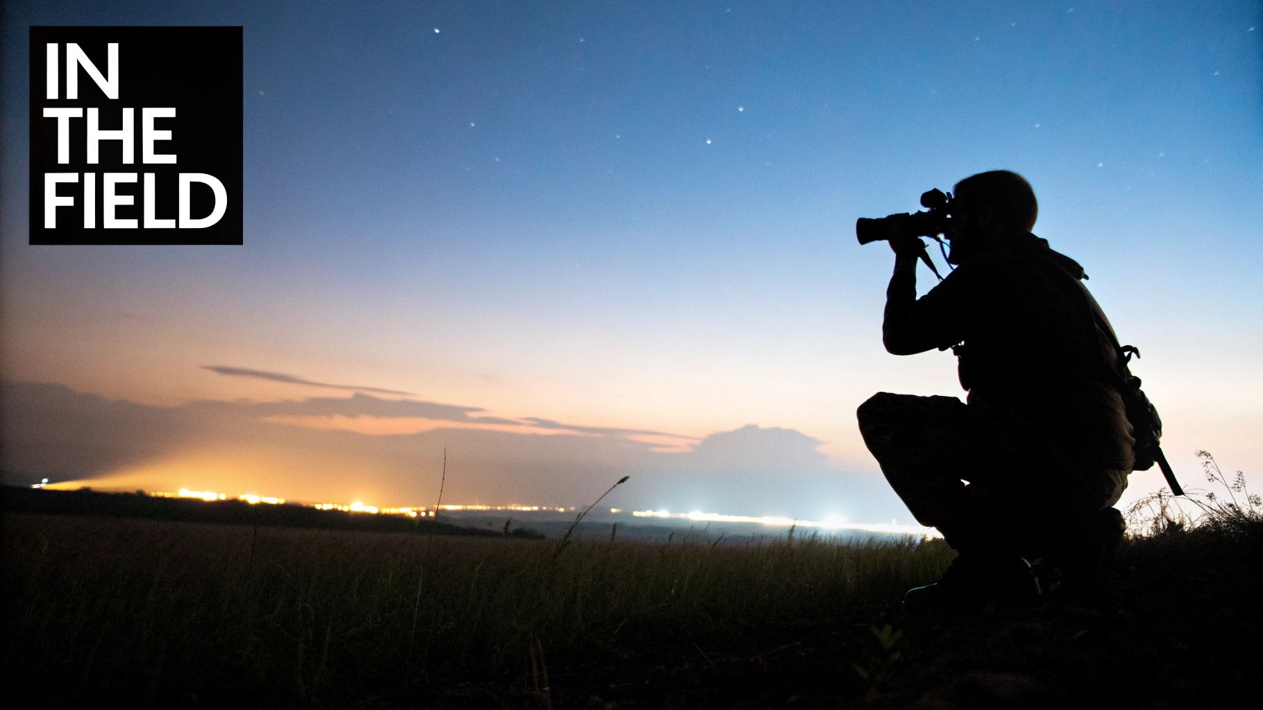 Silhouette of a photographer with a telephoto camera at dusk under a starry sky.