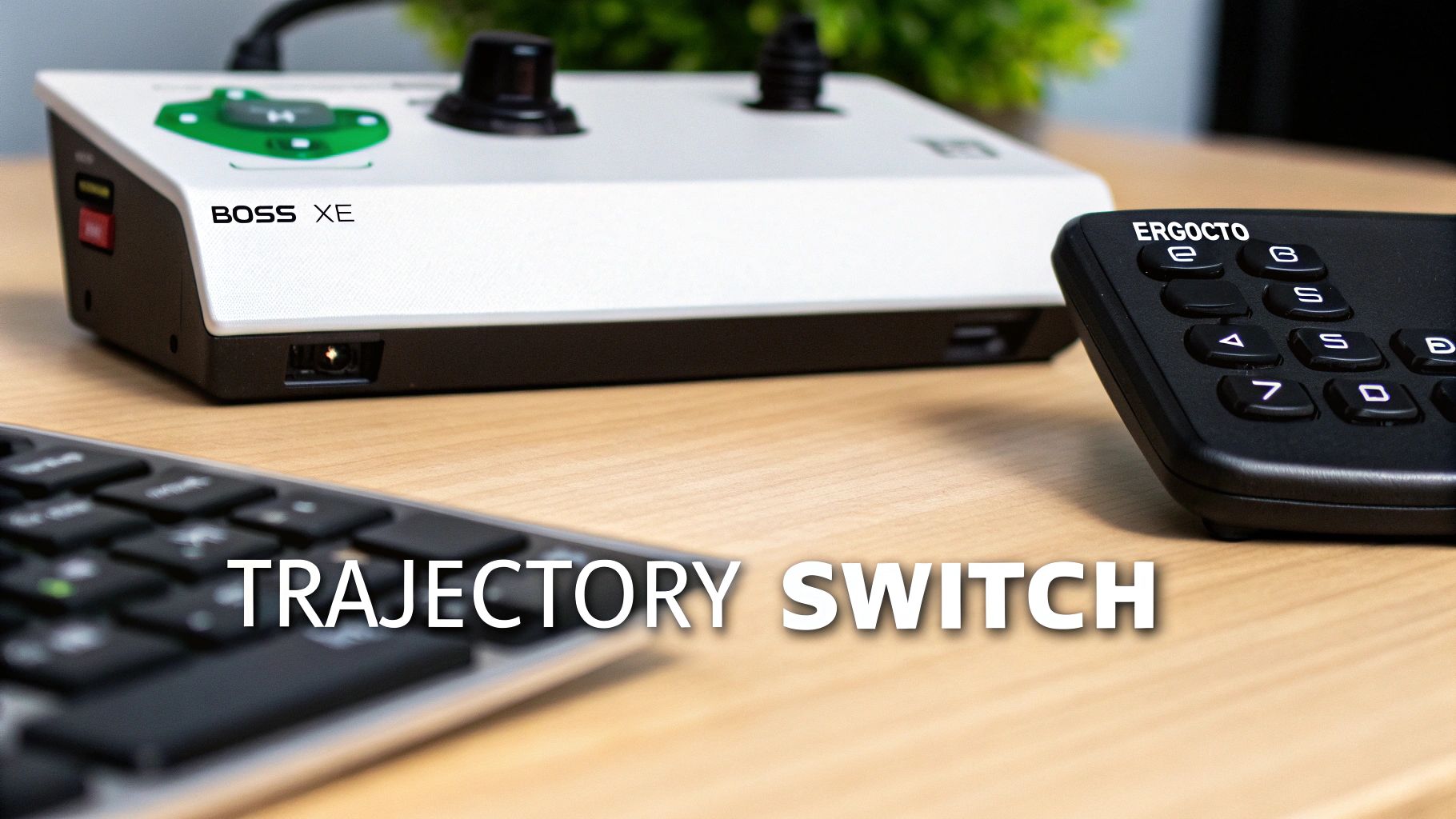 A close-up of a white and black BOSS XE controller, an ERGOCTO keypad, and a keyboard on a wooden desk.