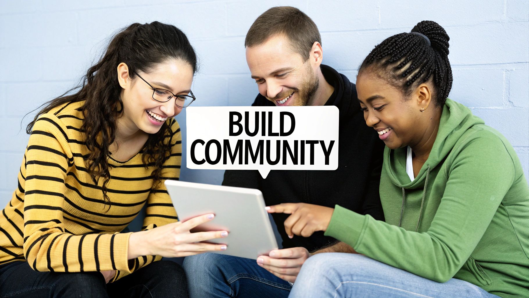 Three diverse people smiling and collaborating around a tablet with 'BUILD COMMUNITY' speech bubble.