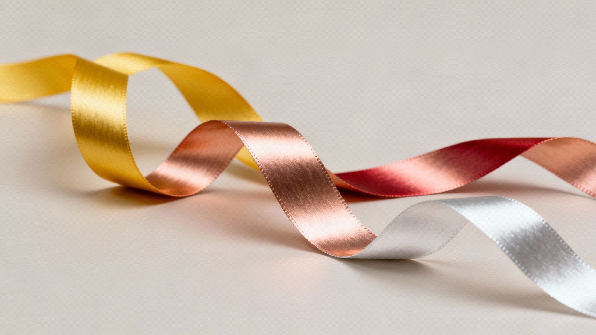 A pair of elegant 18k rose gold rings with intricate designs, resting on a textured white surface.