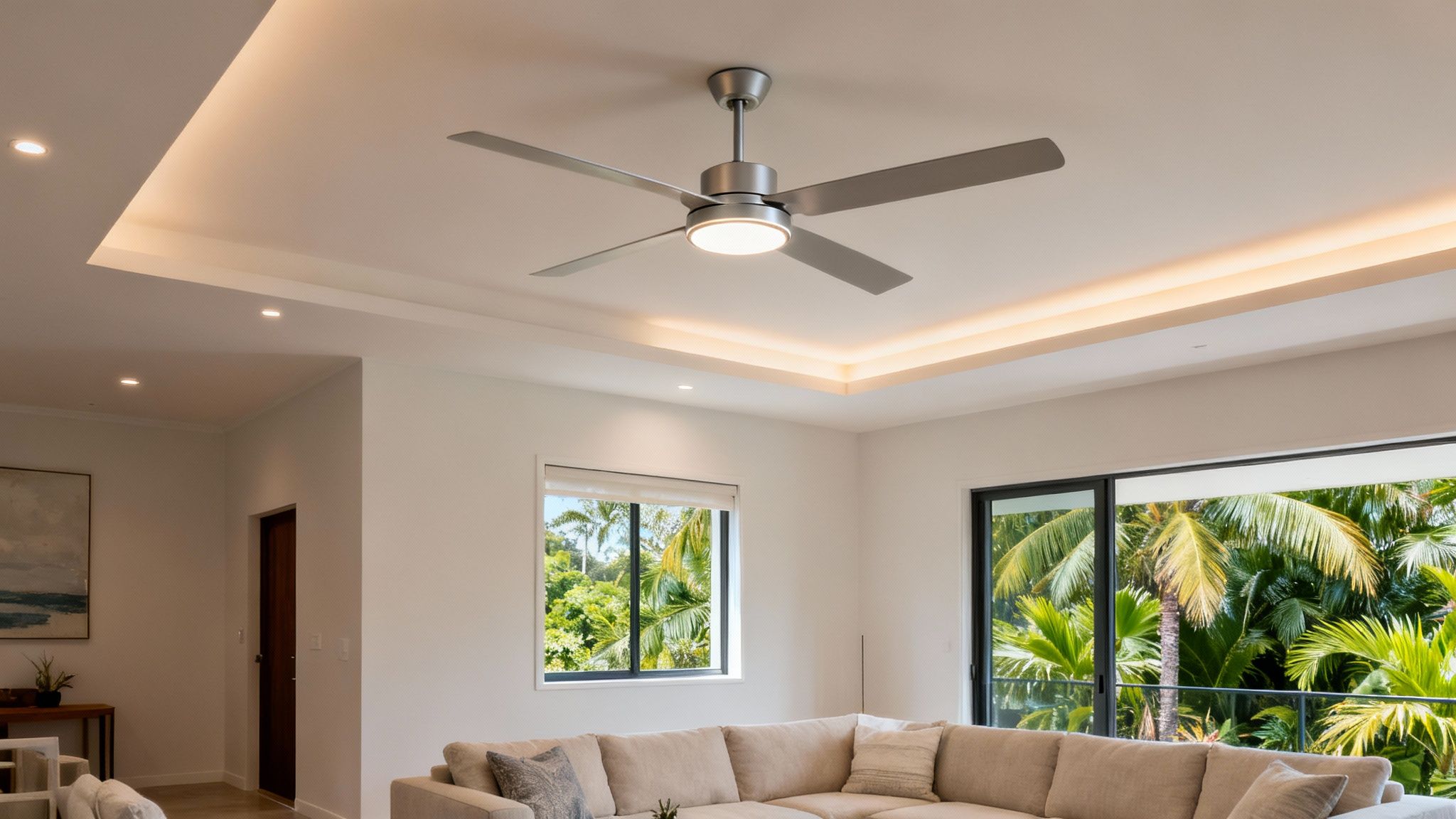 A Bright, Modern Living Room With A Stylish Ceiling Fan, Cove Lighting, And Outdoor Views.