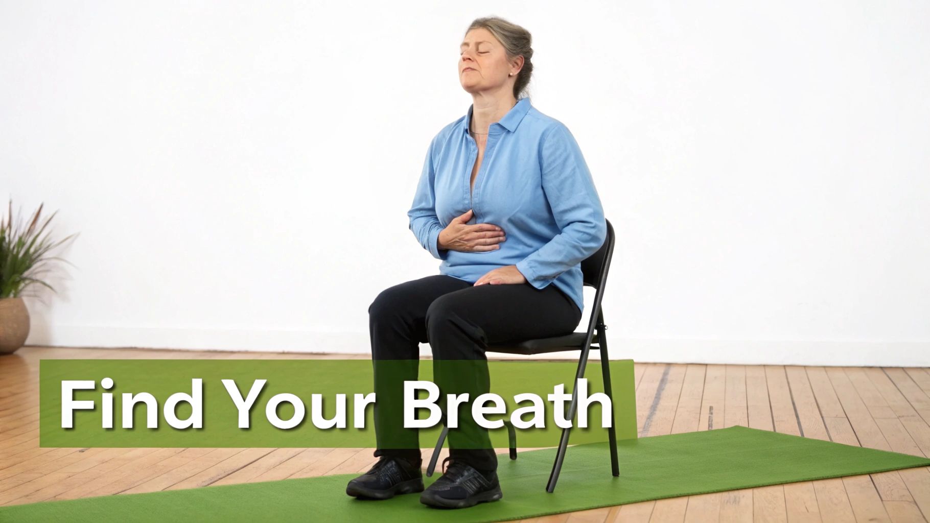 A woman sits on a chair with eyes closed, hands on her stomach, practicing deep breathing.