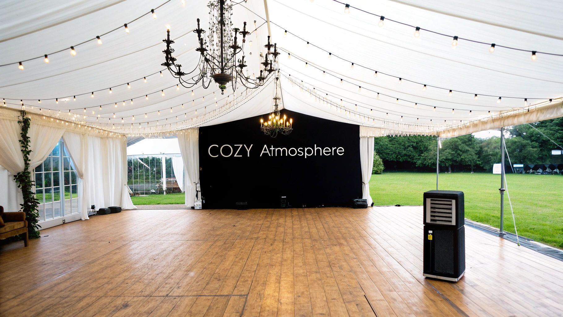 Elegant event tent interior with string lights, chandeliers, wooden floor, and a 'COZY Atmosphere' backdrop.
