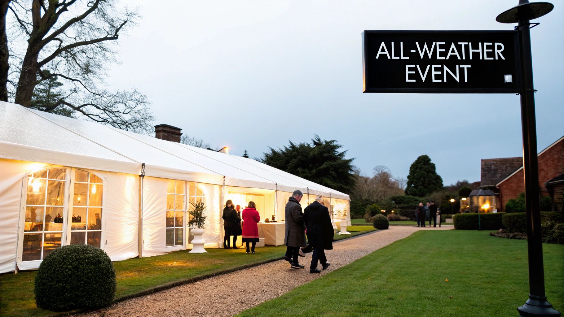 A large white marquee tent illuminated at dusk, with people walking towards an all-weather event.
