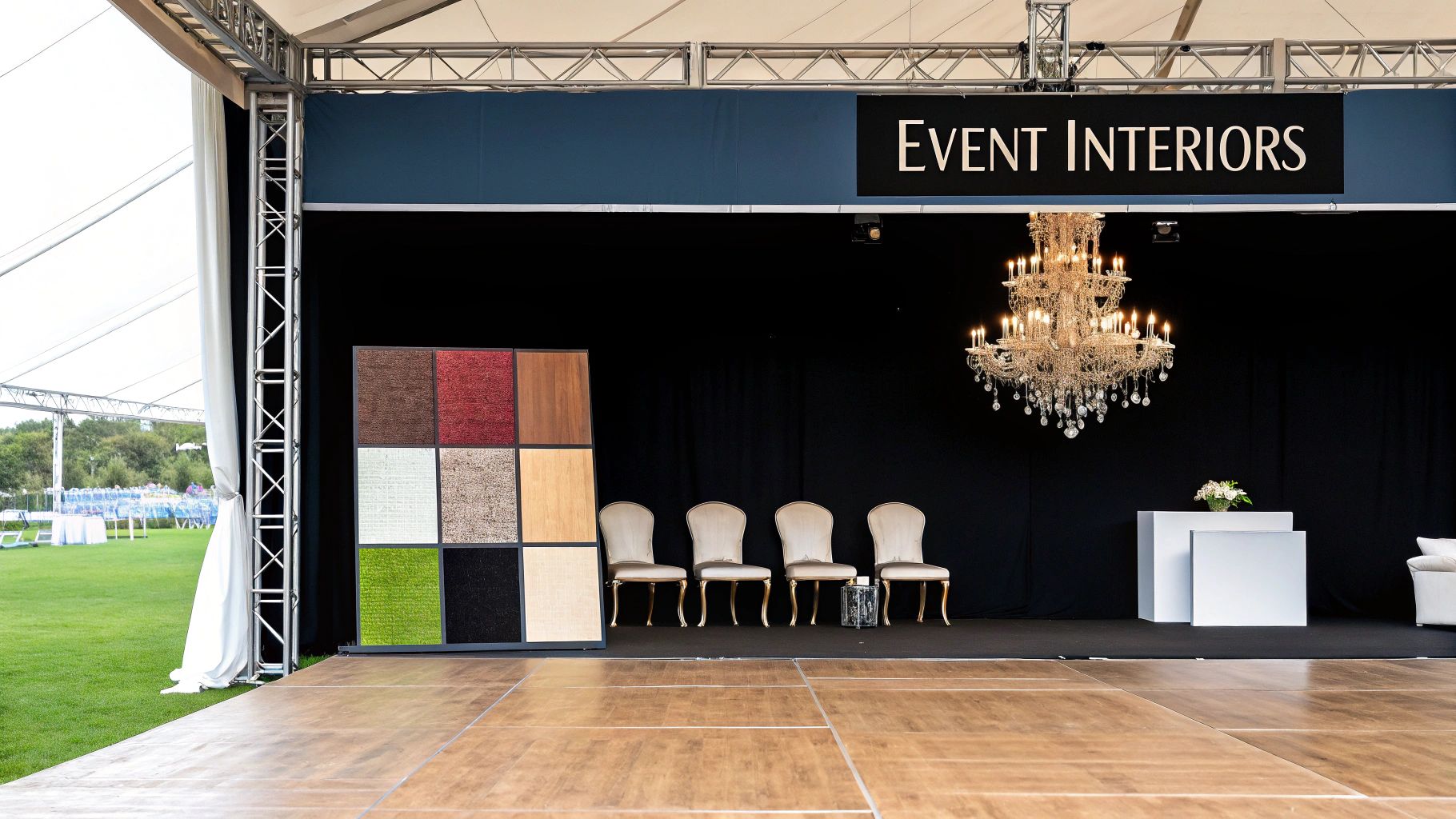 An event interior display inside a marquee, featuring a chandelier, chairs, and material samples.