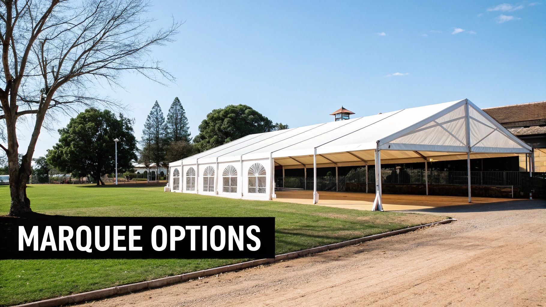 A large white marquee tent with arched windows set up on a green lawn under a blue sky, ideal for events.