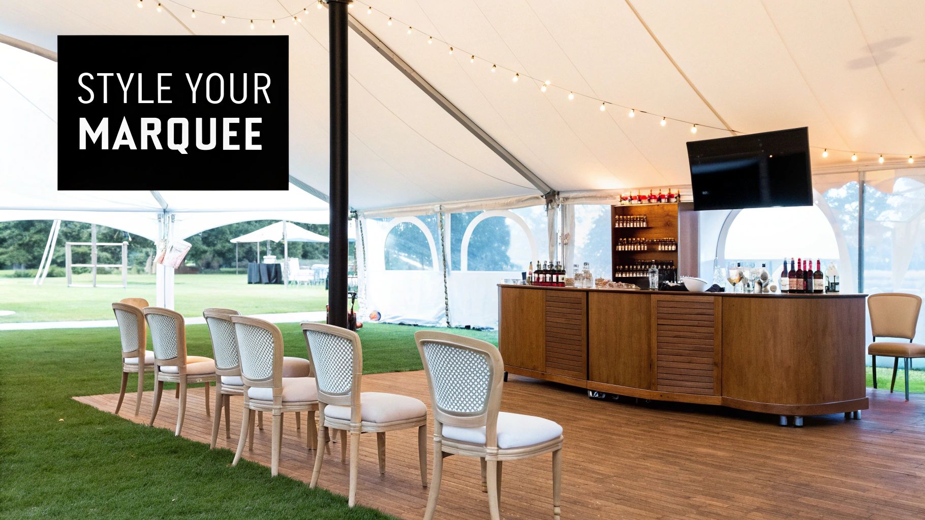 Stylish marquee interior featuring a wooden bar, elegant seating, string lights, and outdoor views.
