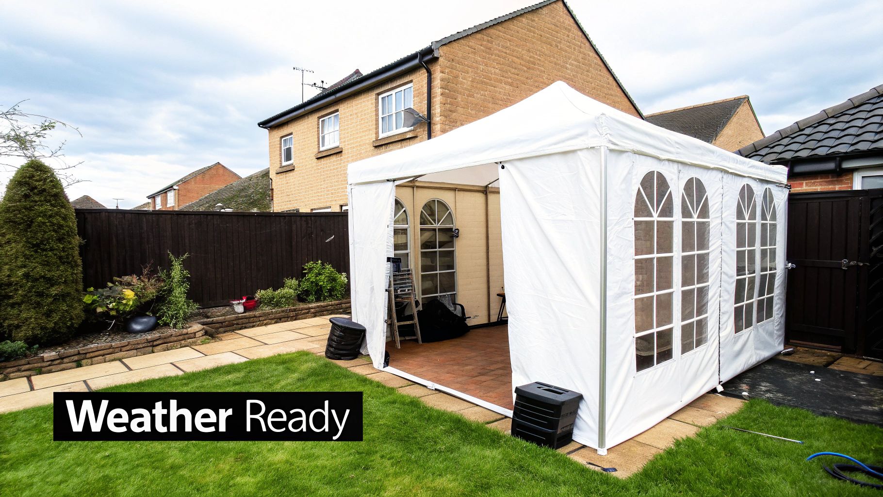 A white weather-ready garden marquee set up on a patio in a backyard.