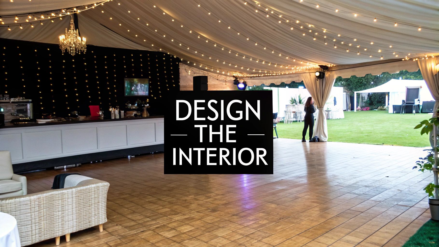 A luxurious marquee tent interior featuring a bar, dance floor, chandelier, and string lights, leading to an outdoor event space.
