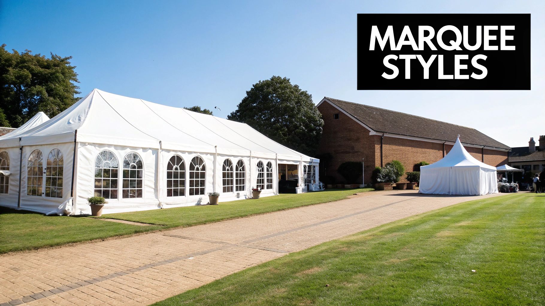 Two white marquees, a large event tent and a pagoda tent, set up on a lawn next to a brick building under a clear blue sky.