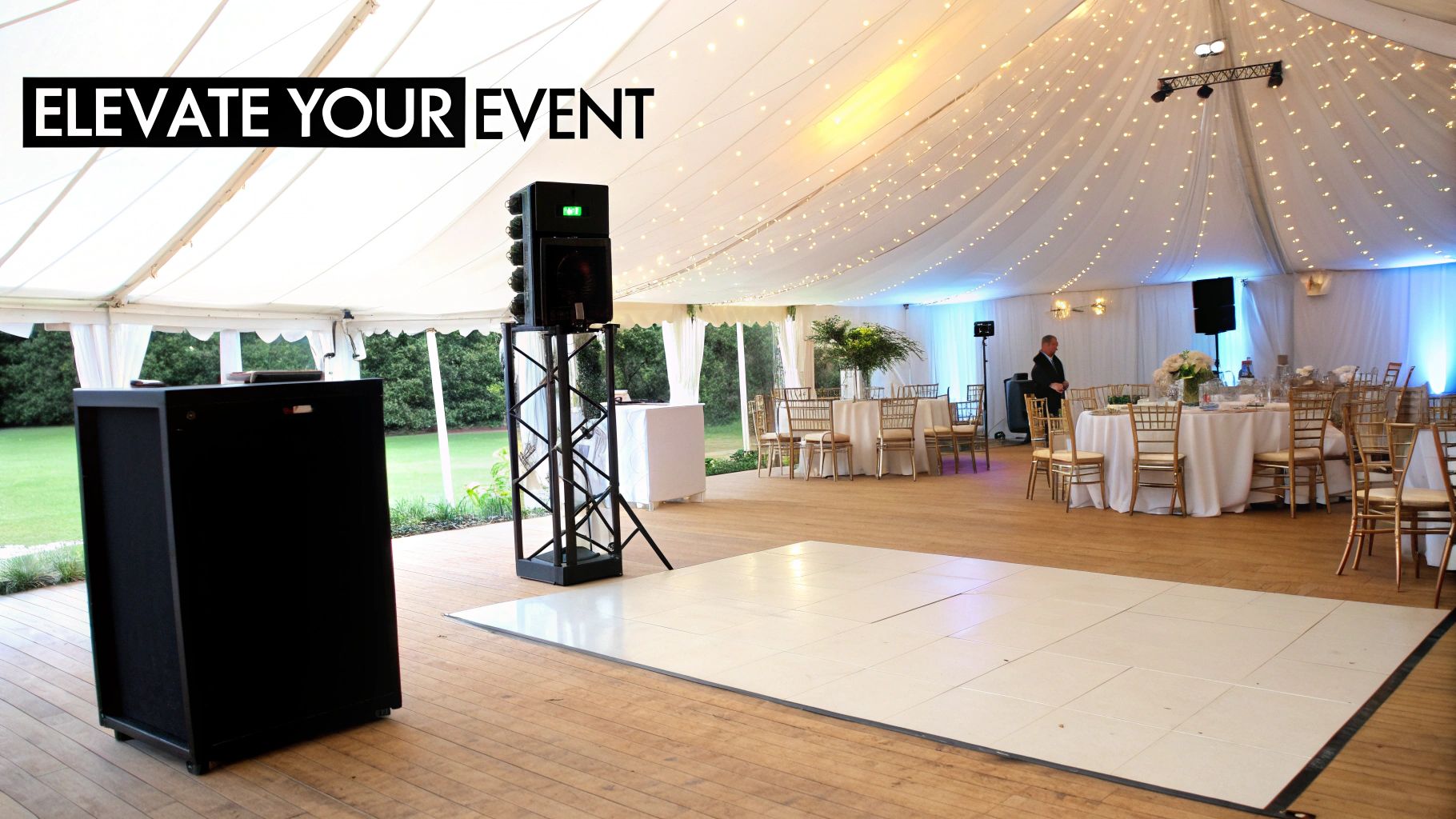 Elegant marquee event tent interior with white dance floor, dining tables, and string lights.