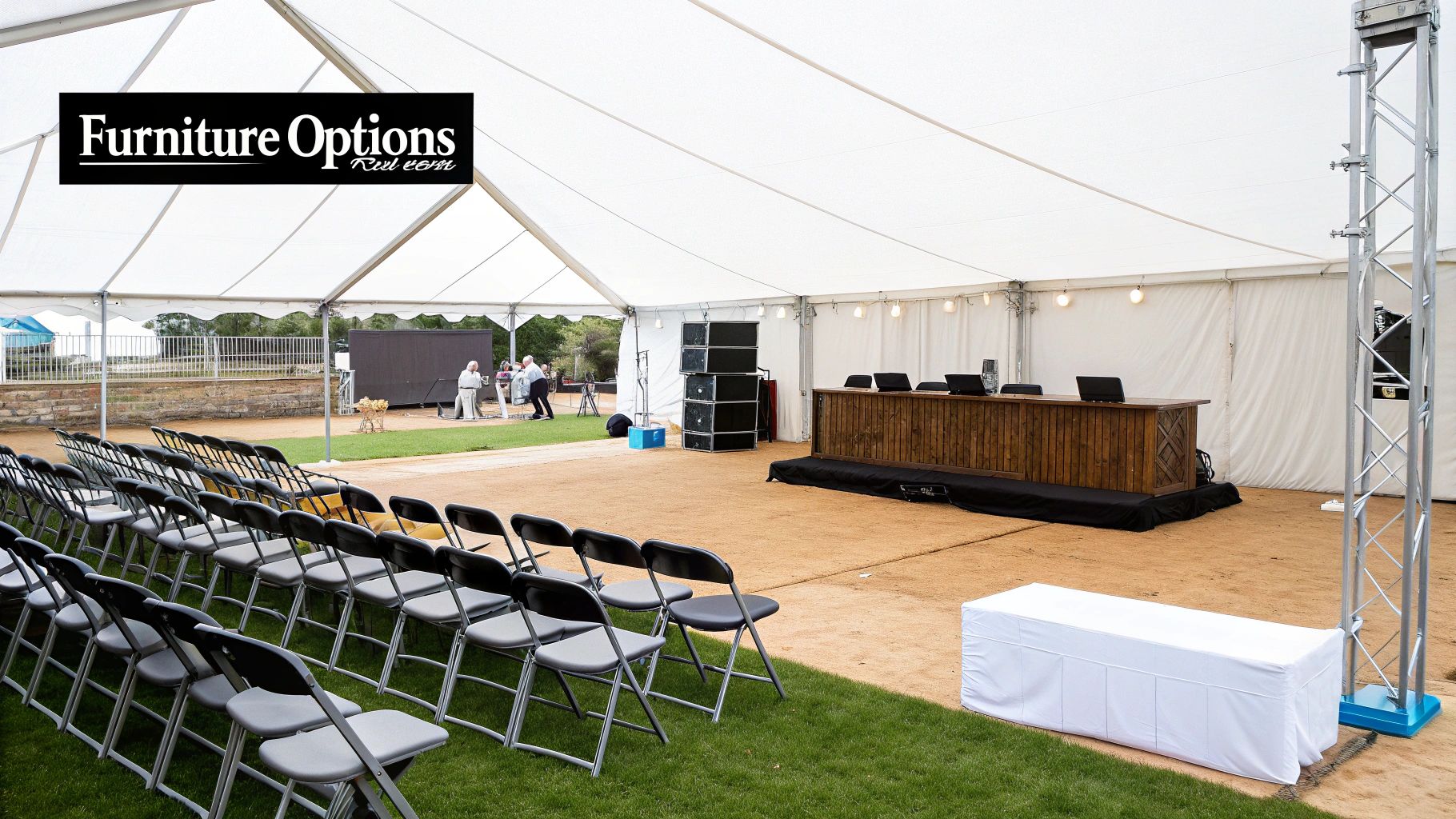An outdoor white marquee tent setup with rows of chairs, a wooden desk, and speakers.