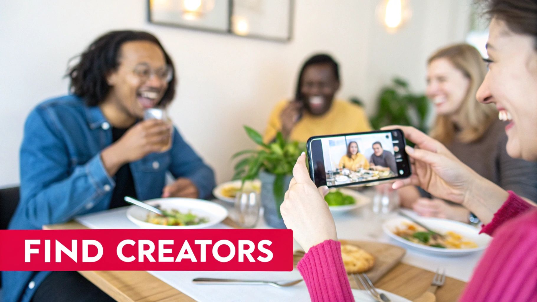 A person capturing smiling friends at a restaurant table with a smartphone, text says 'FIND CREATORS'.