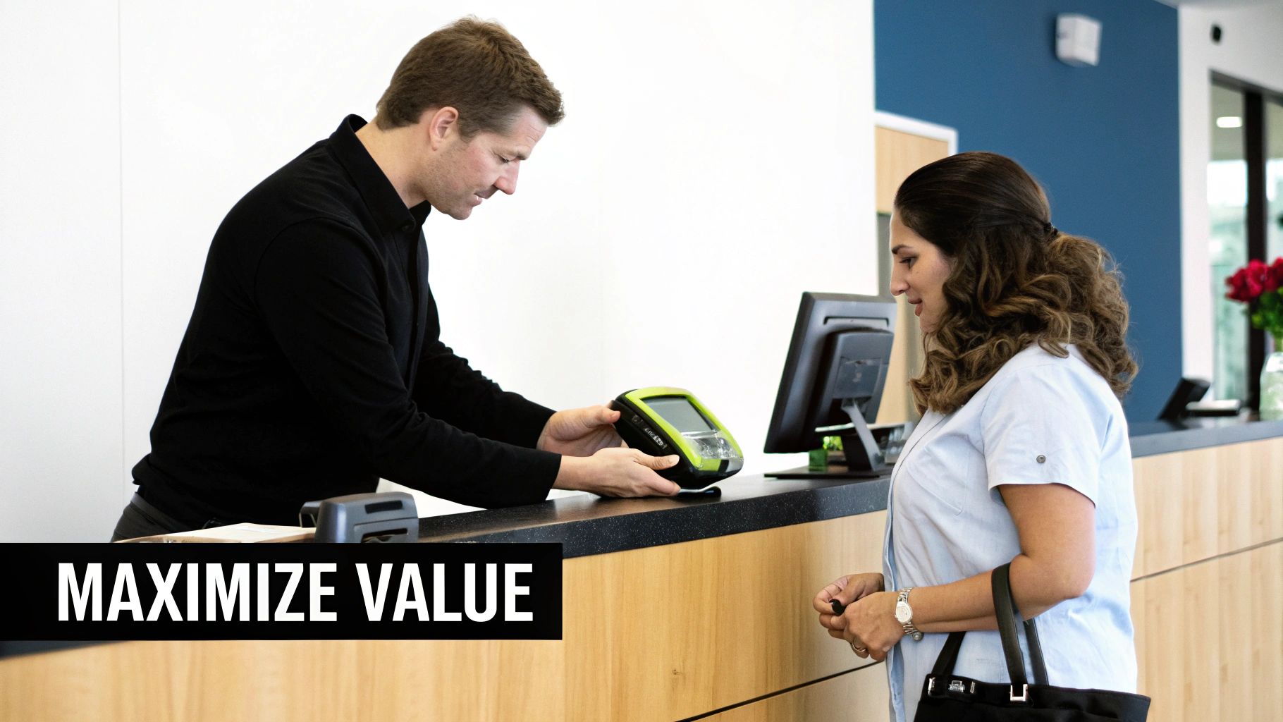 A male staff member hands a green device to a female customer at a service counter.