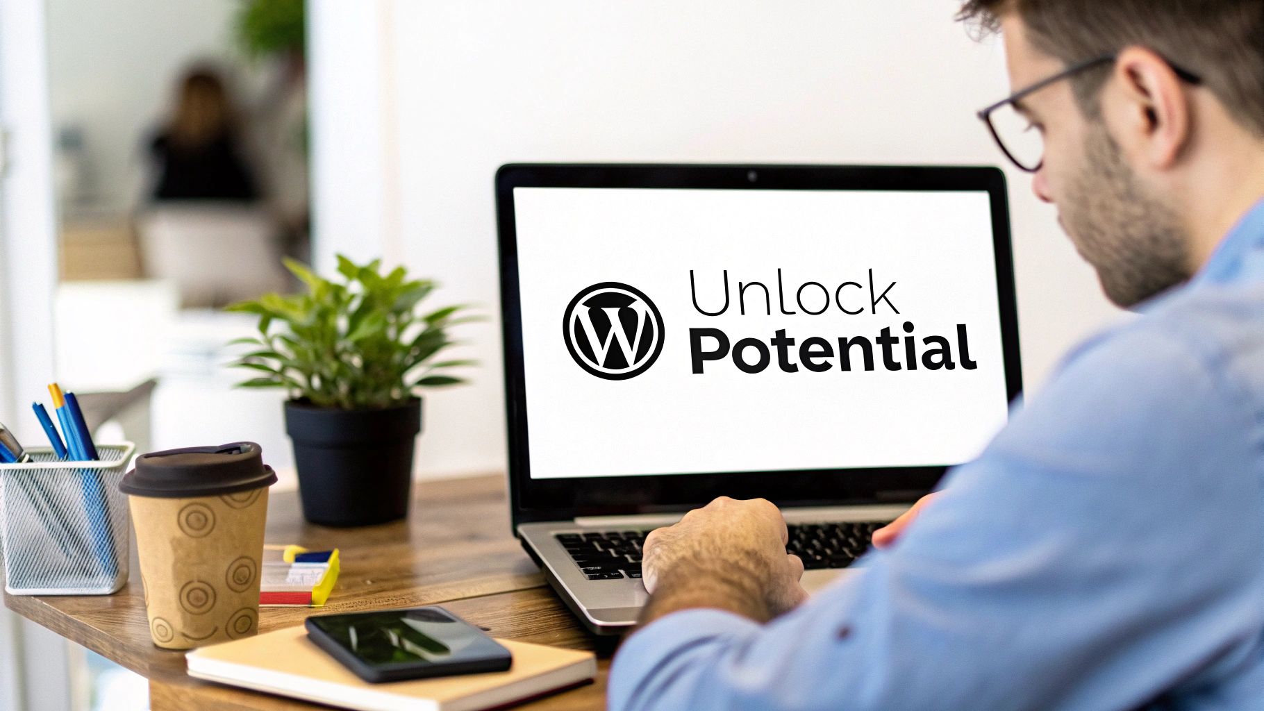 A person with glasses works on a laptop displaying the WordPress logo and 'Unlock Potential' text.