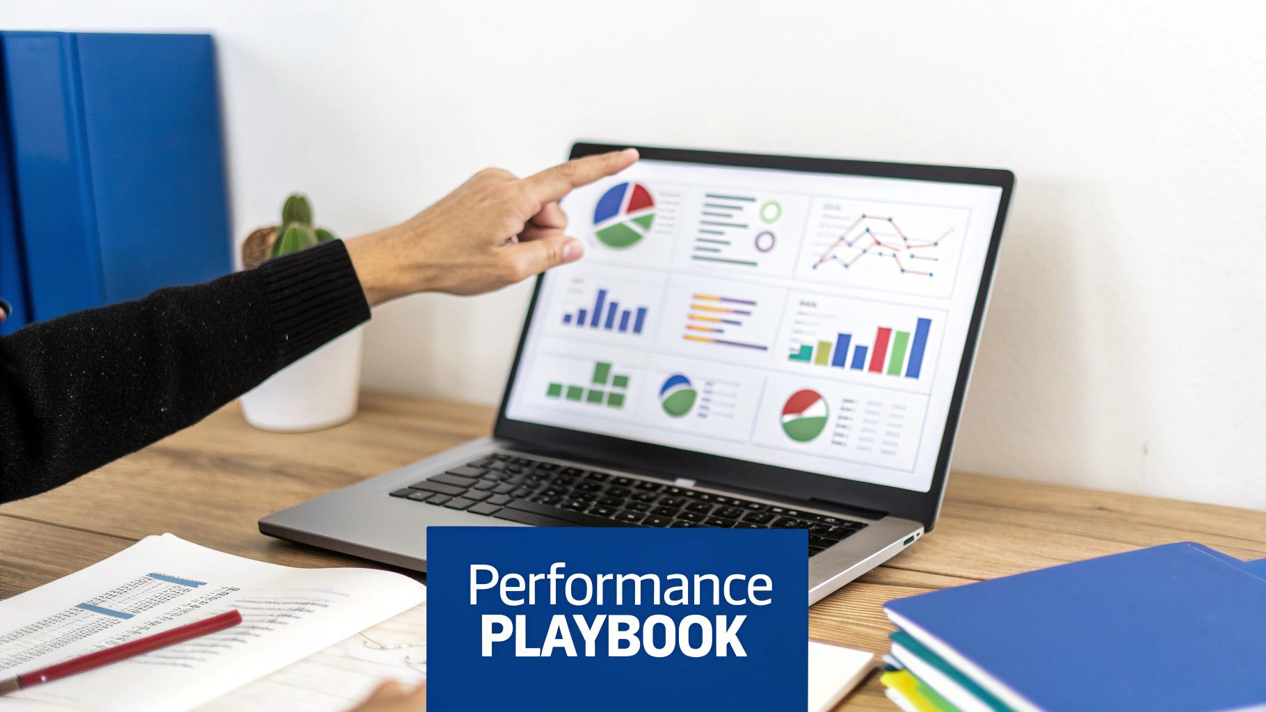 A hand points at a laptop displaying colorful business performance charts and graphs on a wooden desk with documents.