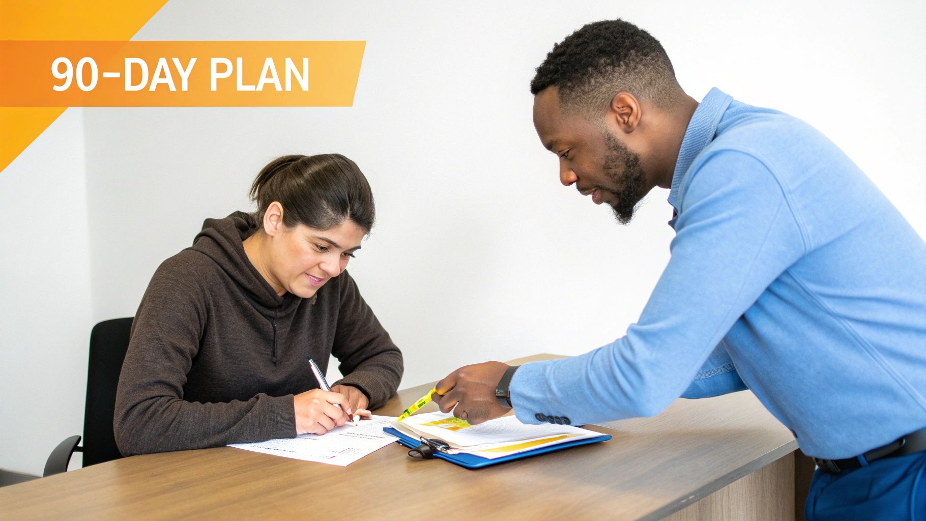 A man points to a document for a woman writing at a desk, with '90-DAY PLAN' visible.