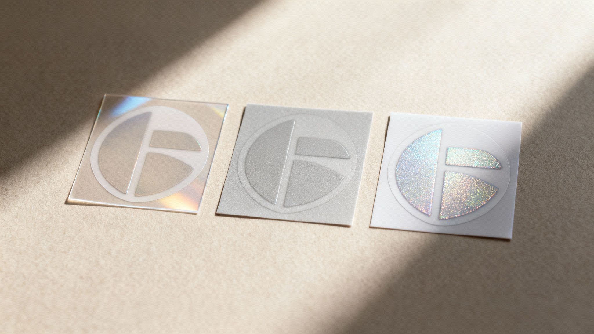 A hand holding up a freshly printed vinyl sticker with a glossy finish that catches the light.