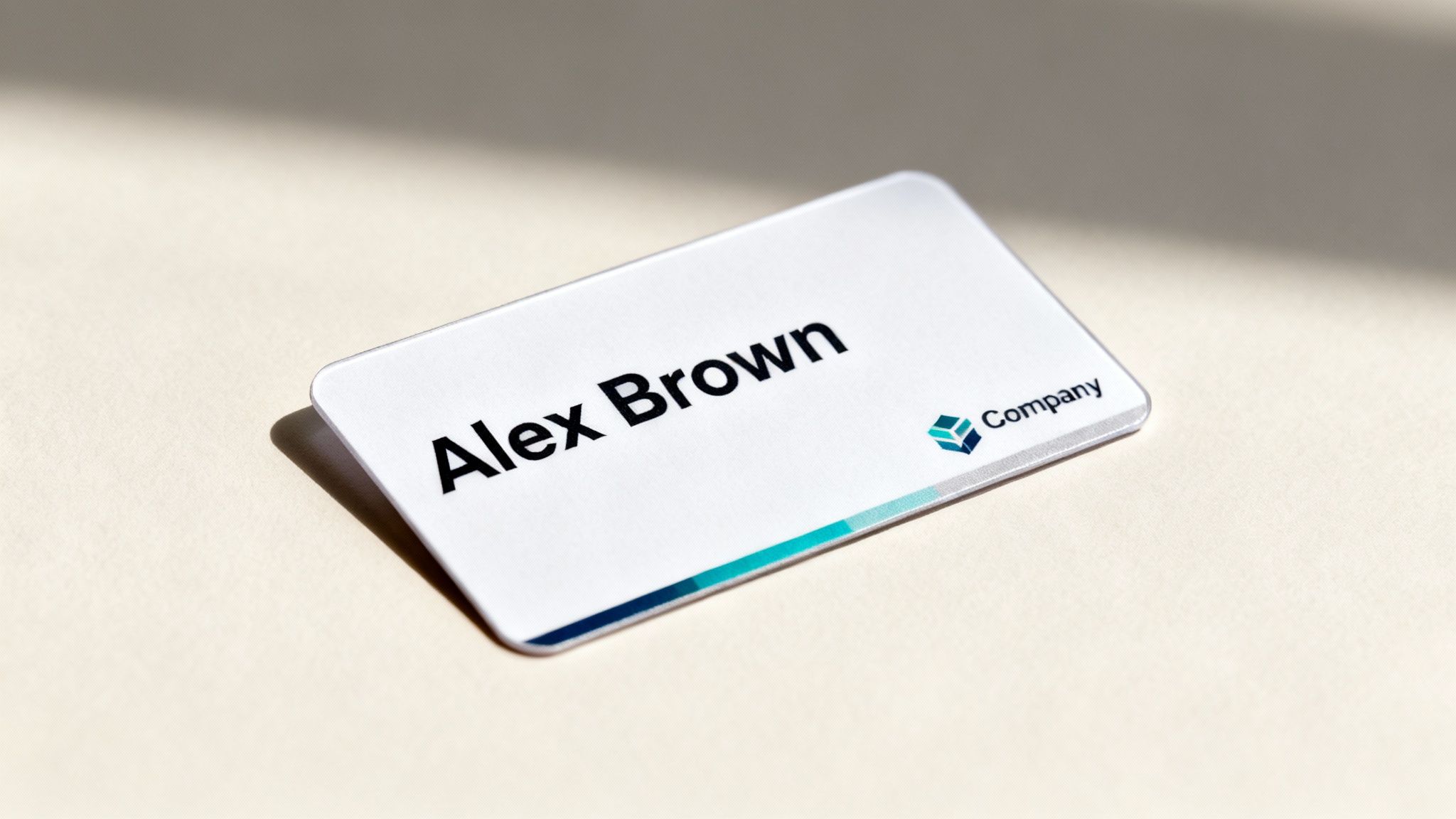 A white name badge displaying 'Alex Brown' and a company logo, resting on a textured surface.