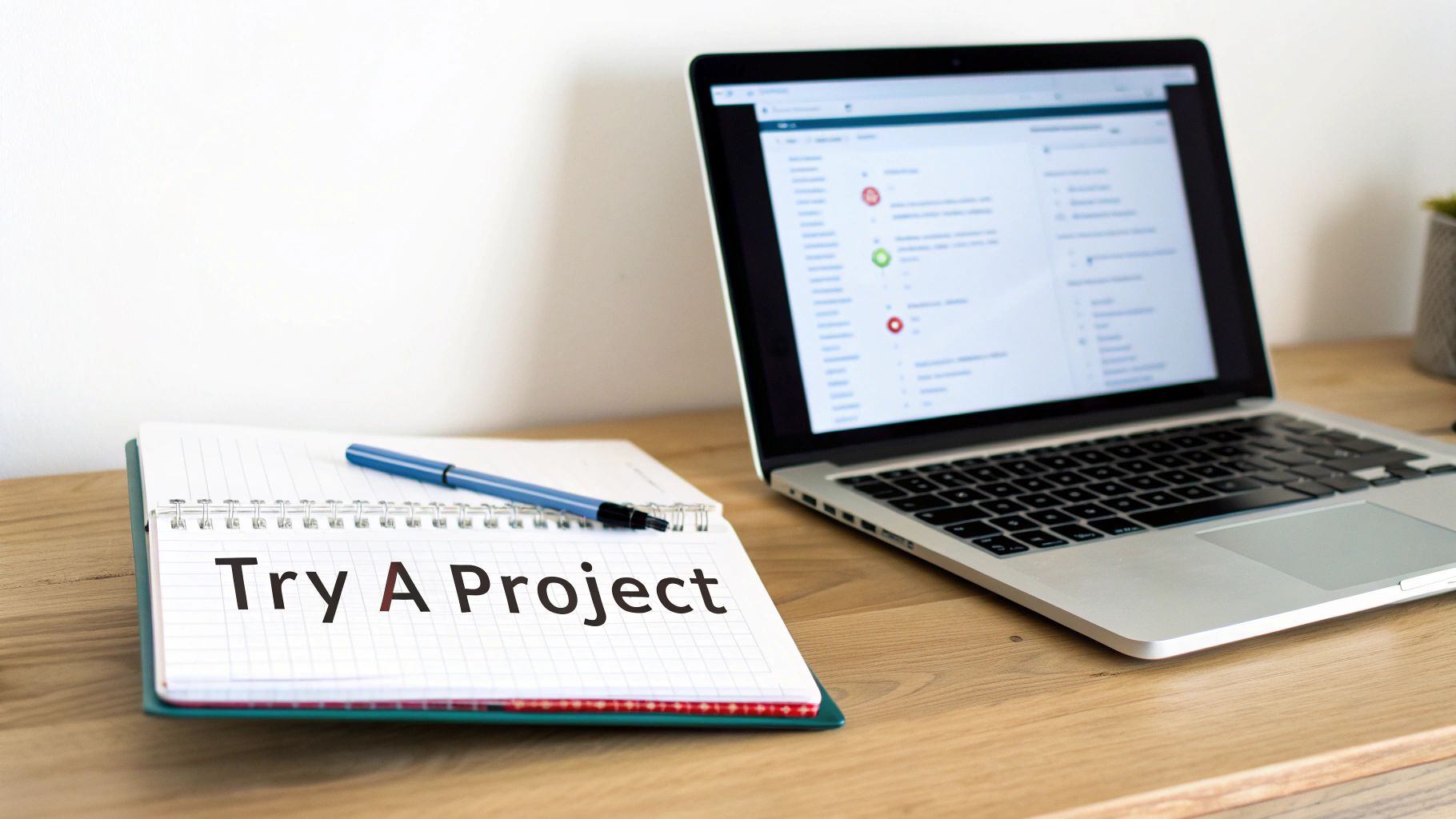 Workspace with an open laptop, a notebook featuring 'Try A Project' text, and a pen.