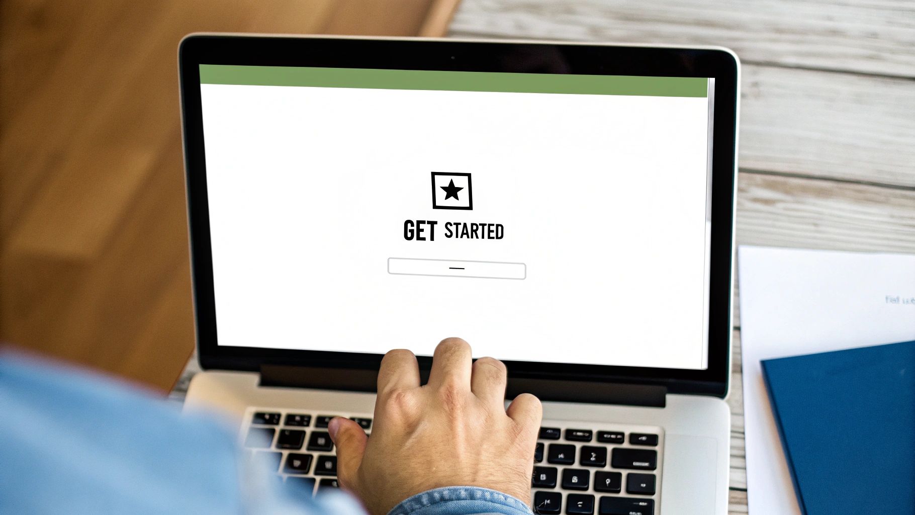 A person typing on a laptop displaying a 'GET STARTED' page with a star icon and an input field.