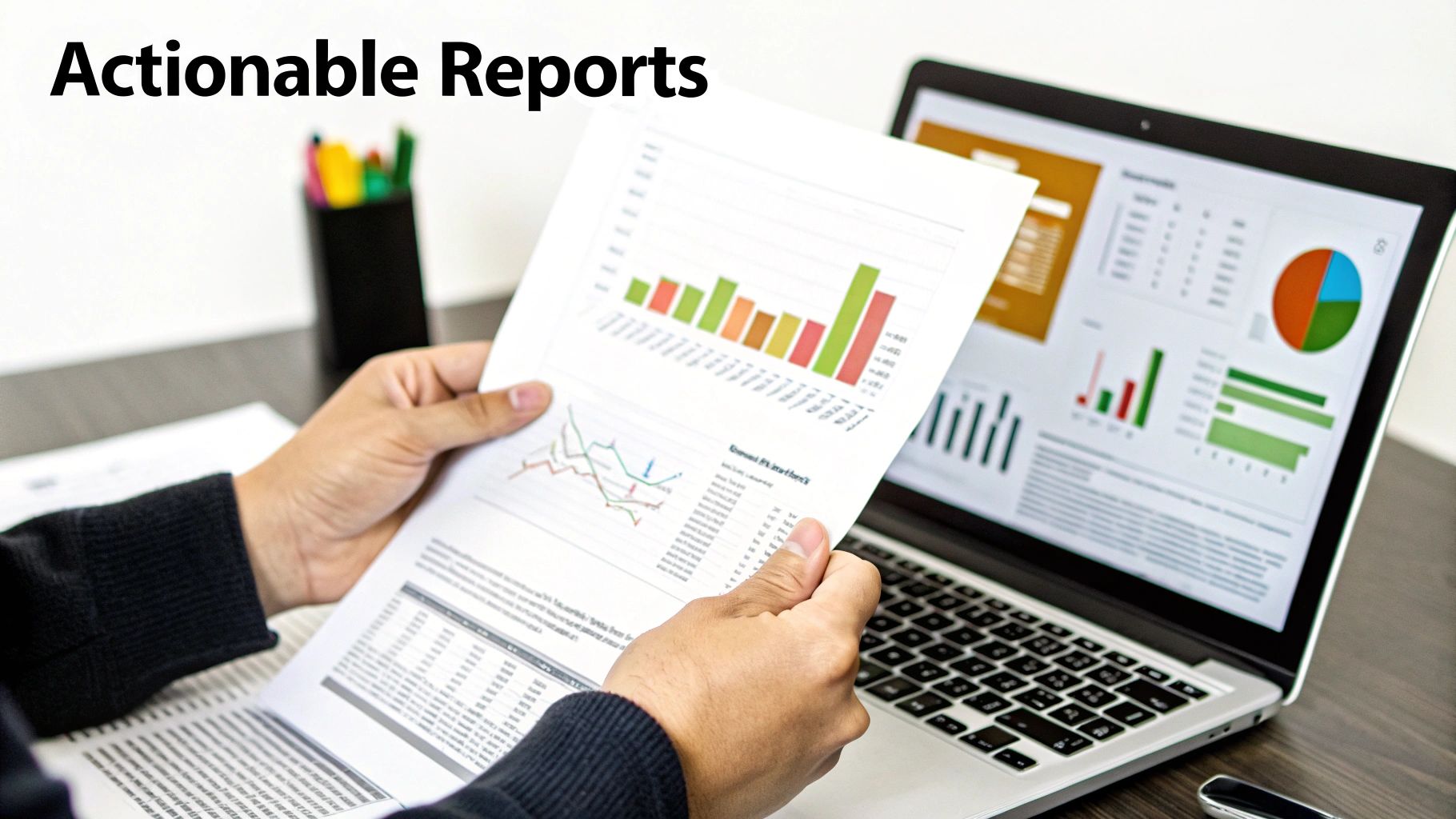 Person analyzing a printed business report with graphs and charts next to a laptop displaying data dashboards.