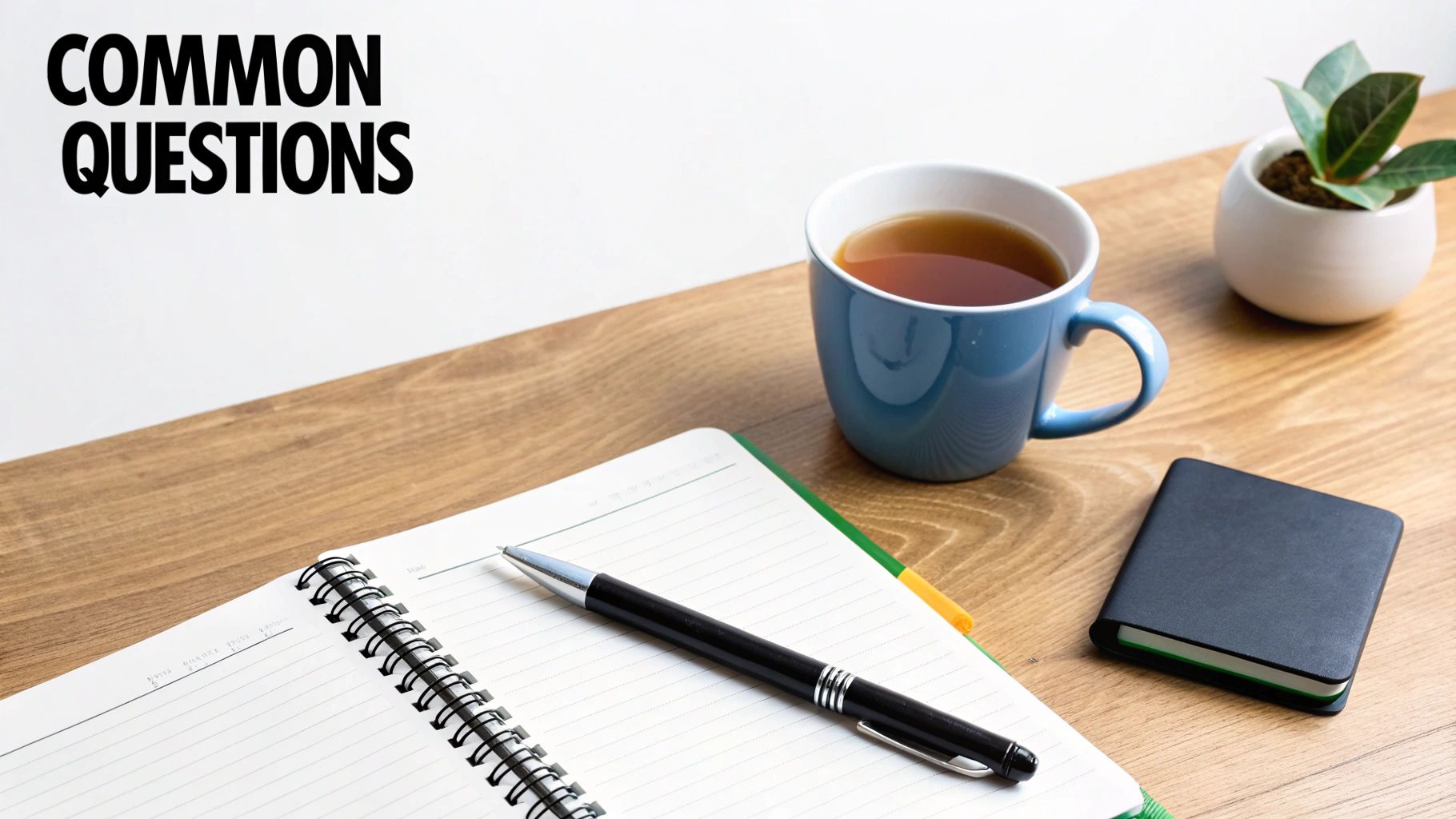 Common questions text above a workspace with a notebook, pen, coffee, and small plant.