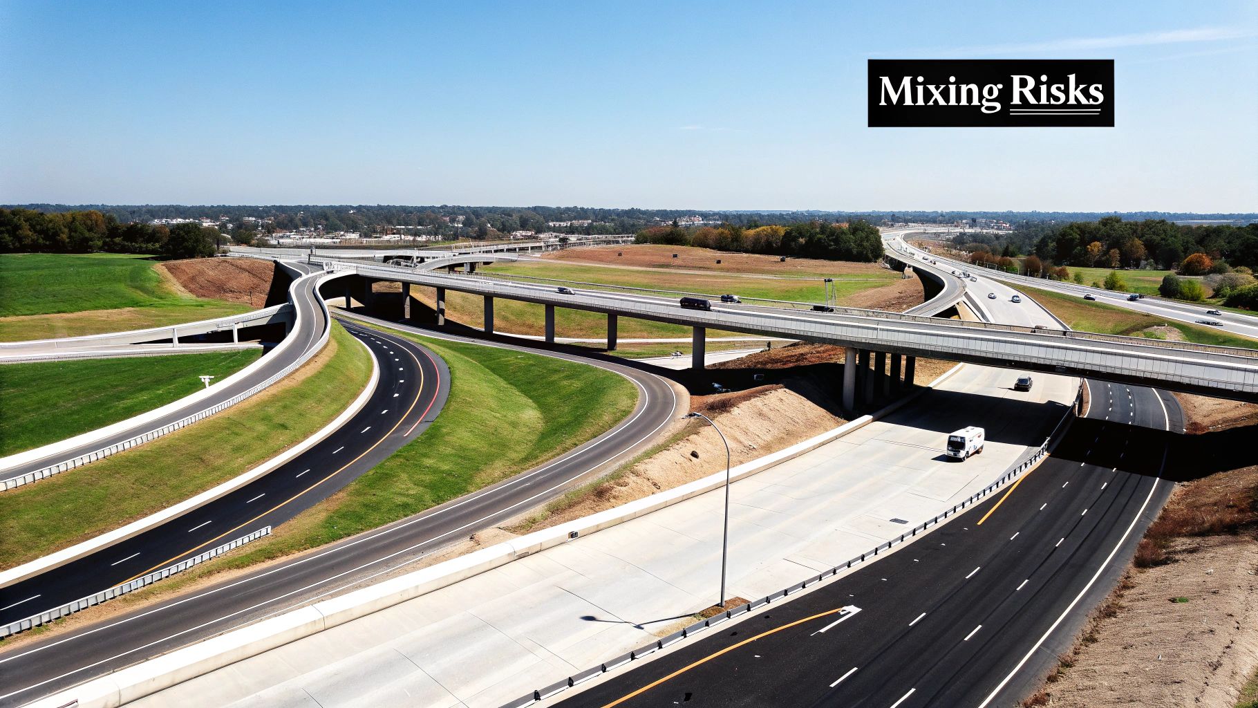 An aerial view of a complex highway interchange with multiple roads, cars, and green grassy areas.
