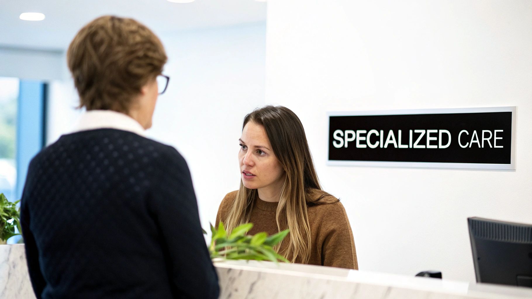 Patient consulting with healthcare professional at specialized care reception desk in modern medical clinic