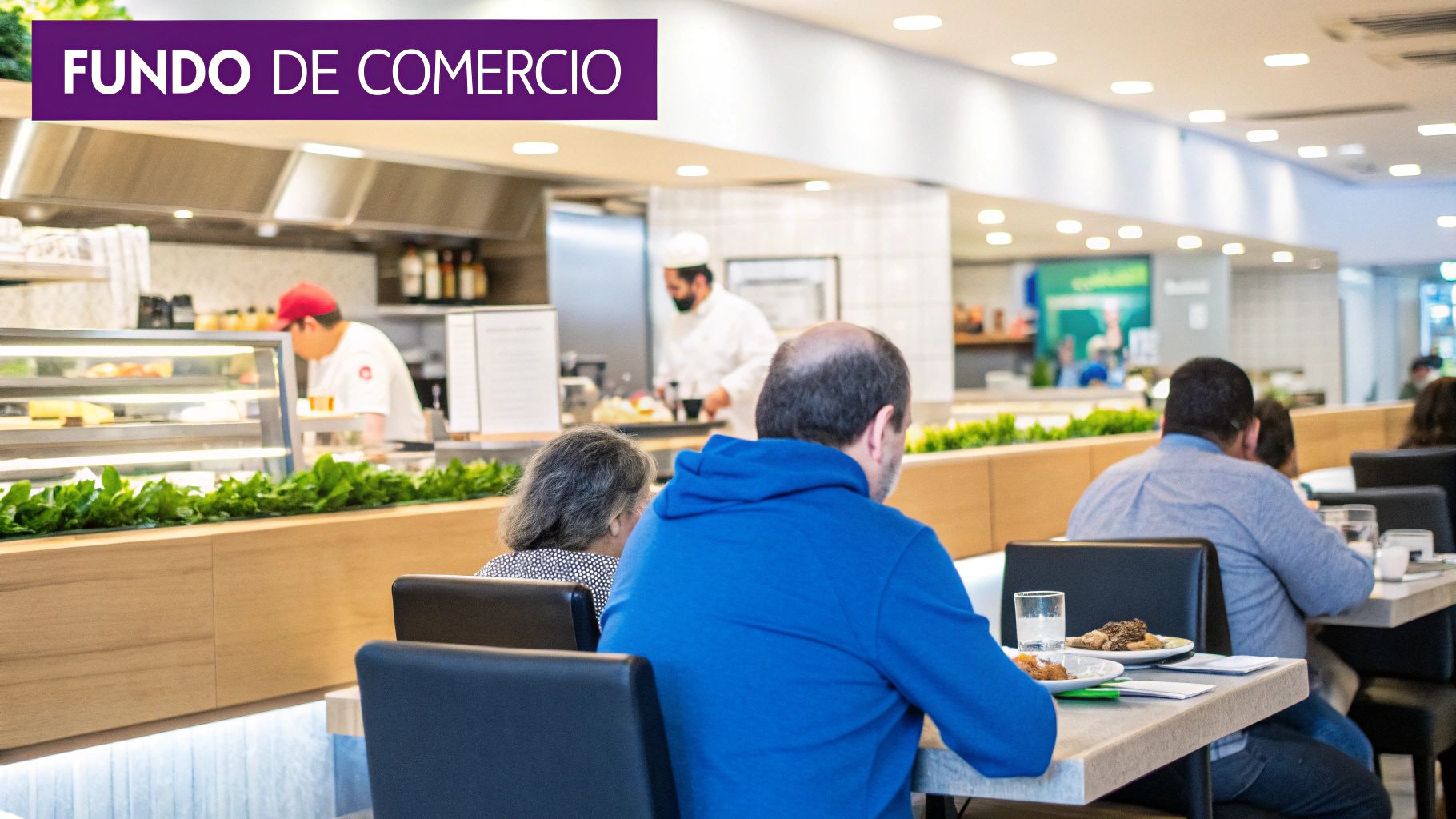 Pessoas almoçando em restaurante moderno com cozinha aberta e chefs trabalhando, ideal para 'Fundo de Comércio'.