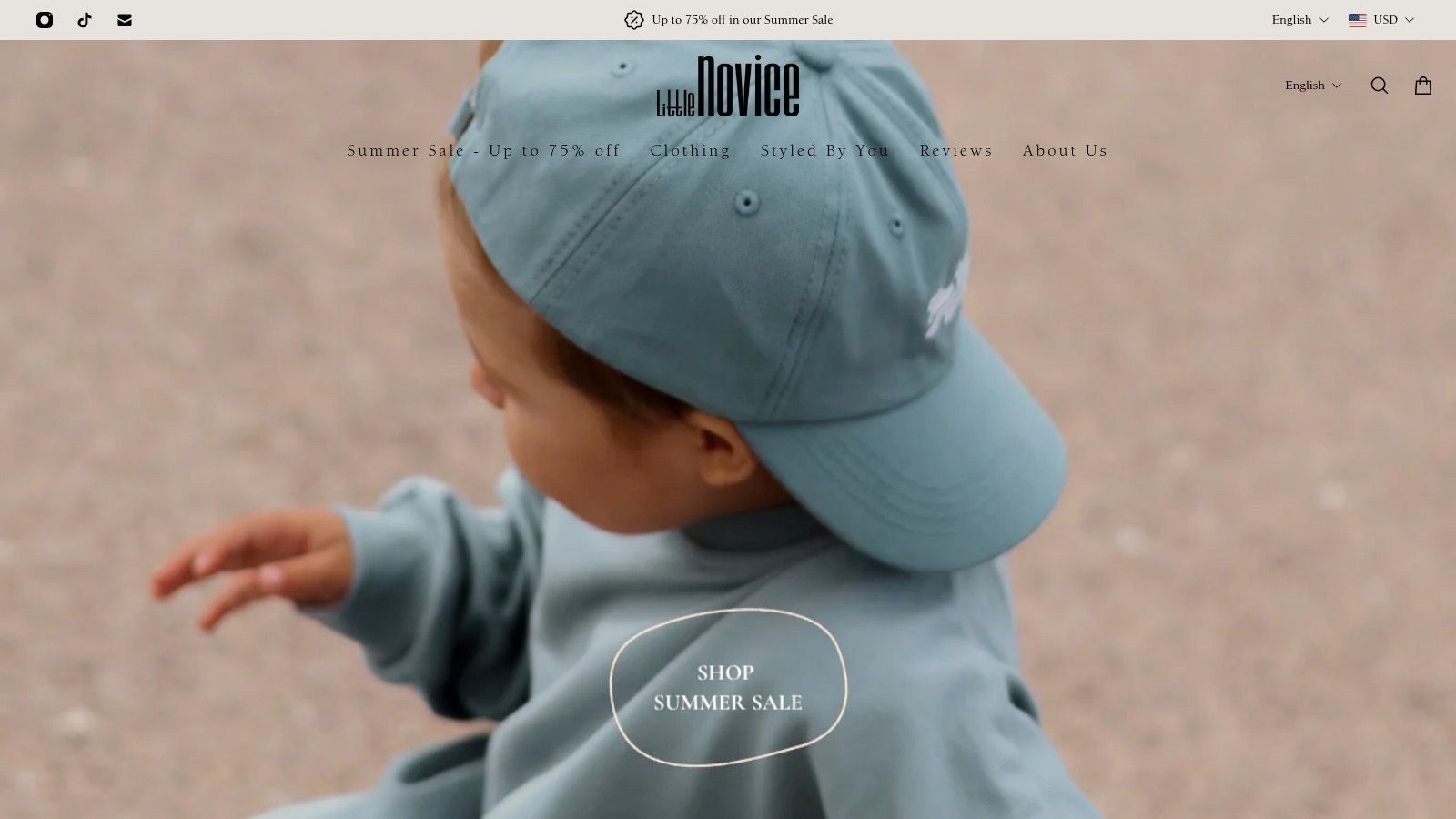 A collection of minimalist, neutral-toned organic cotton baby clothes from Little Novice, neatly folded.
