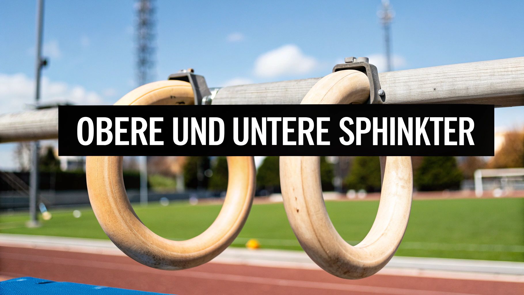 Zwei hölzerne Turnringe hängen an einer horizontalen Stange über einem Sportplatz. Ein schwarzes Banner mit dem Text „OBERE UND UNTERE SPHINKTER“ verdeckt die Mitte.