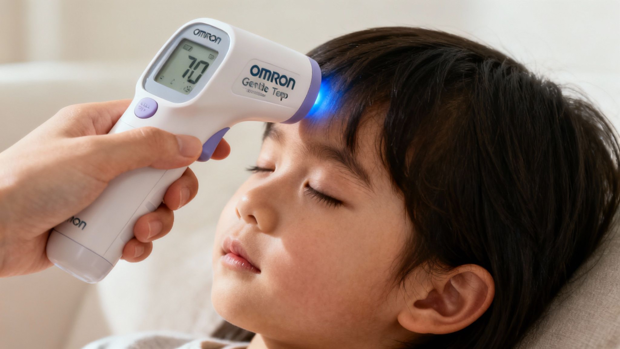 O mână ține termometrul Omron Gentle Temp 720 la distanța corectă de fruntea unui copil.