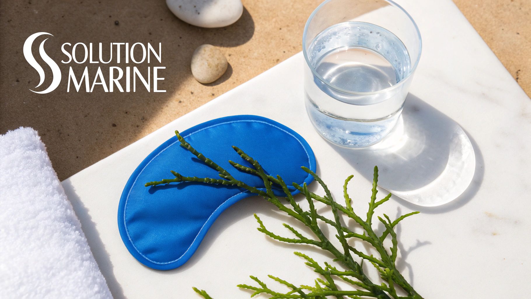 Logo Solution Marine avec masque pour les yeux bleu, algues, verre d'eau, serviette blanche sur marbre et sable.