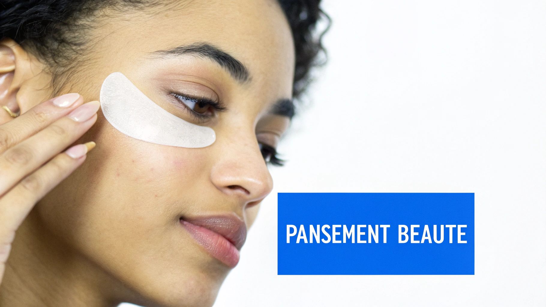 Une jeune femme applique un patch anti-cernes sous les yeux, geste de beauté et soin de la peau.