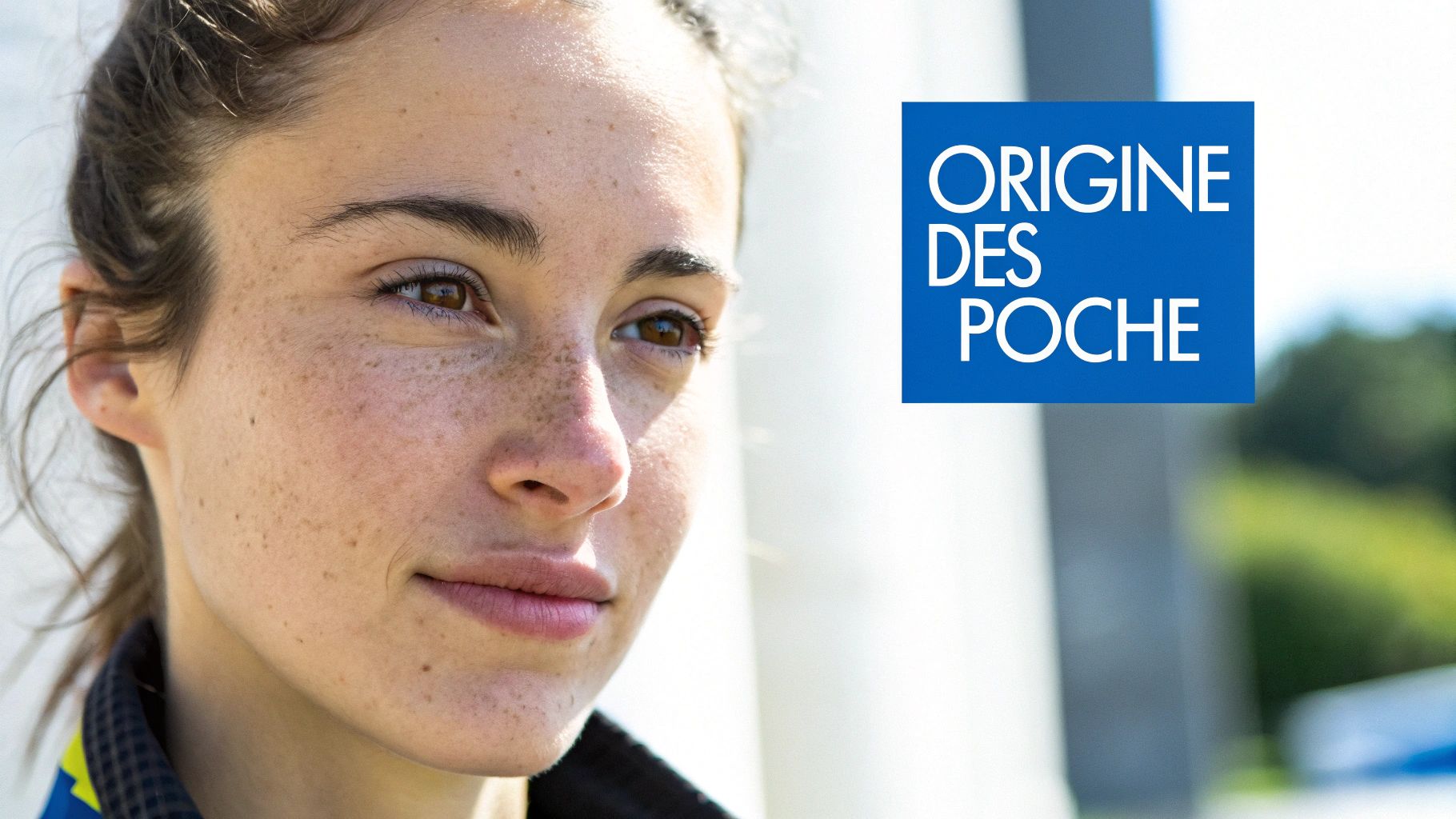 Gros plan sur le visage naturel d'une jeune femme aux taches de rousseur, regardant sur le côté, avec un logo bleu.