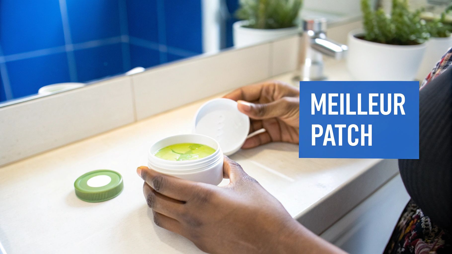 Mains tenant un pot ouvert de crème verte dans une salle de bain lumineuse avec un miroir.