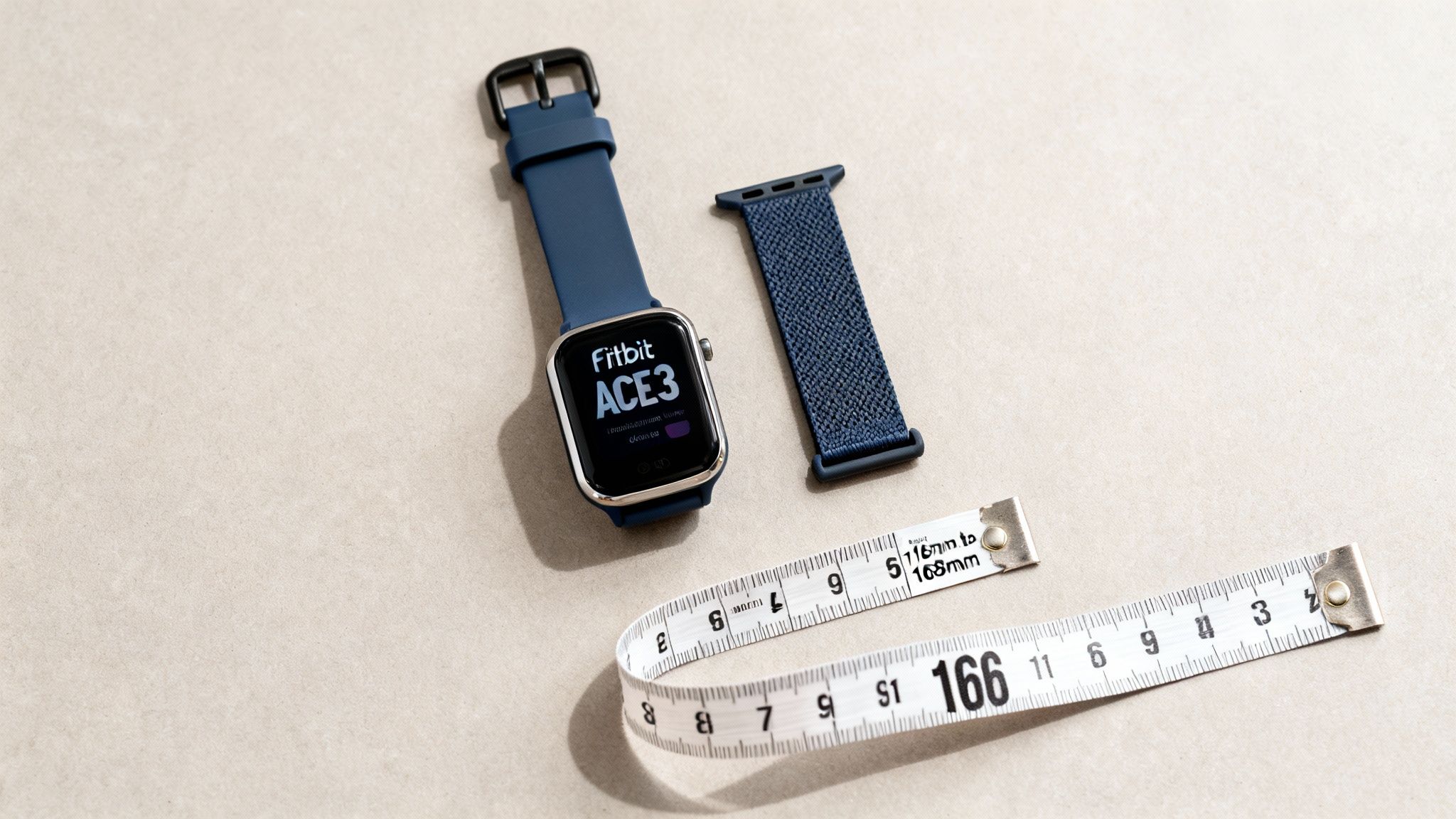 Blue Fitbit Ace 3 watch, an extra strap, and a measuring tape for sizing.