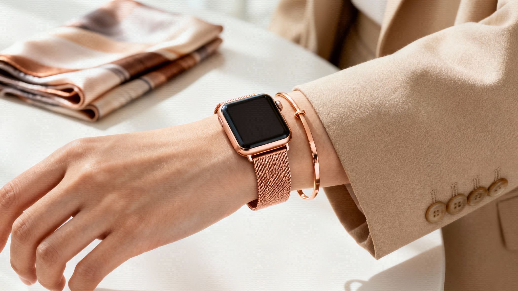 A woman's arm showcasing a rose gold Apple Watch with a Milanese loop band and matching bracelet.