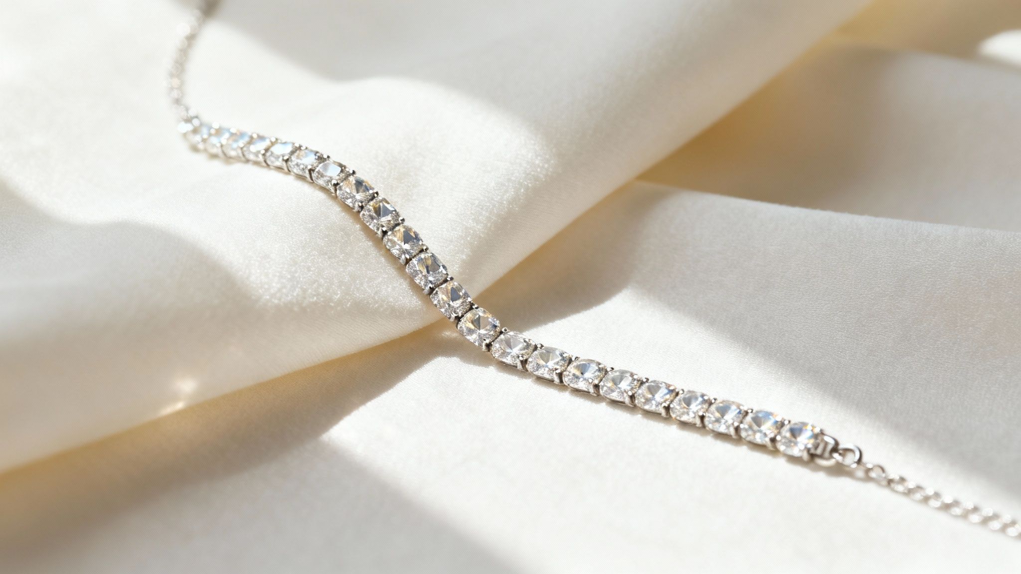 Elegant tennis bracelet with brilliant clear stones displayed on soft, light-colored satin.