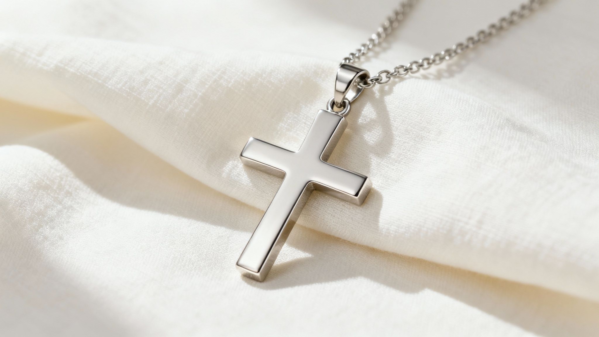 A close-up of a delicate gold cross pendant necklace resting on a white surface