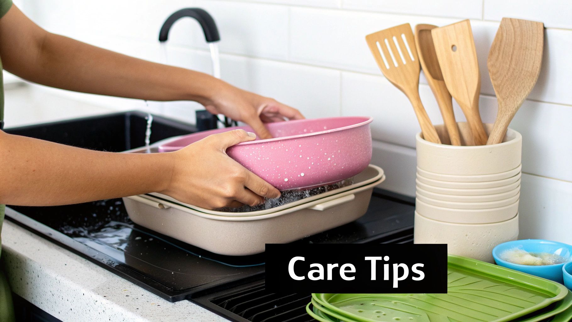 A person is washing a pink cooking pot in a kitchen sink with wooden utensils nearby.