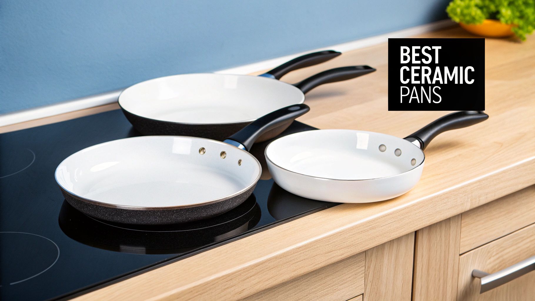 Three white ceramic frying pans with black handles on a kitchen induction hob and wooden countertop.