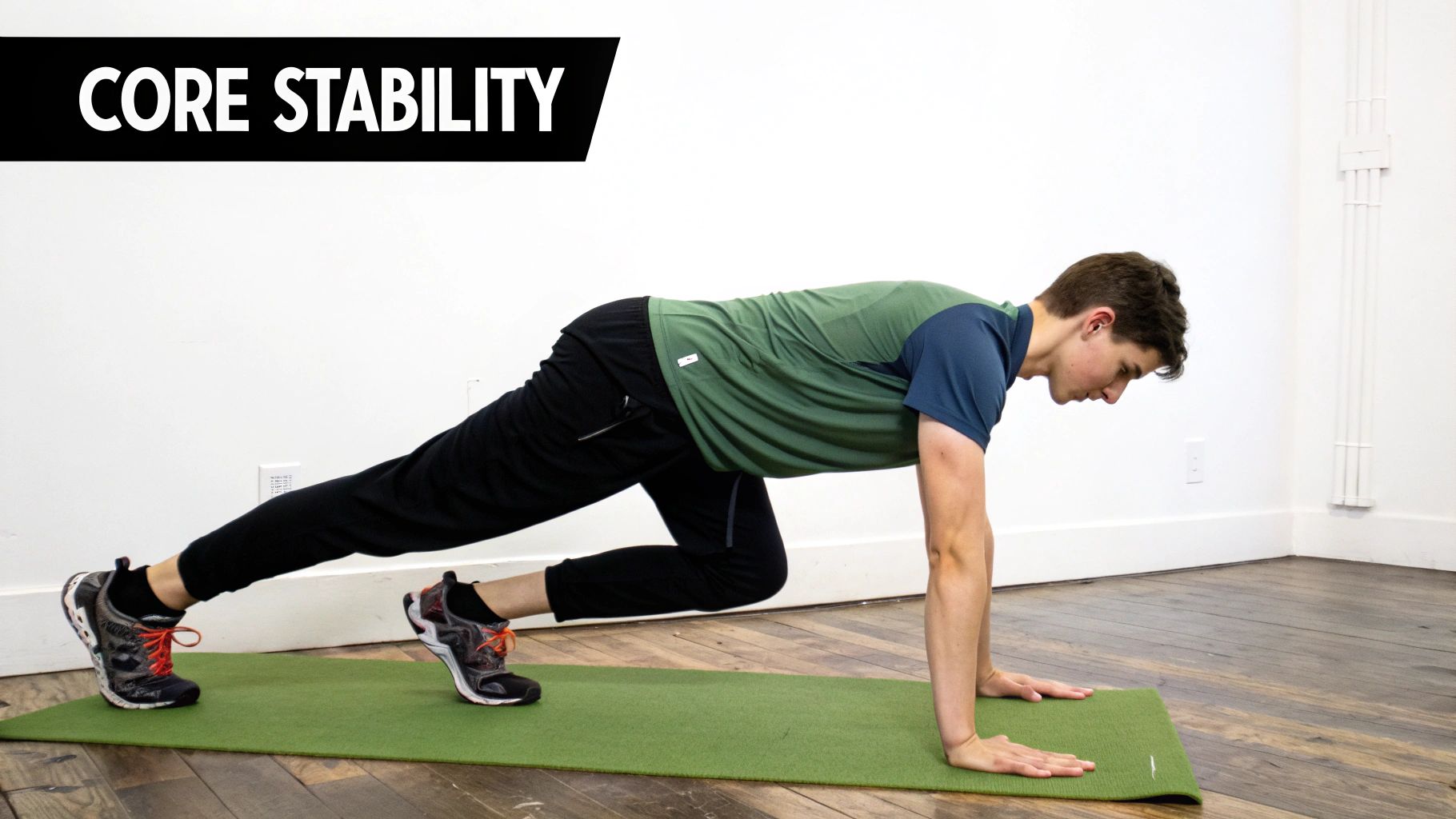 A young man demonstrates a core stability exercise resembling a mountain climber on a green mat.