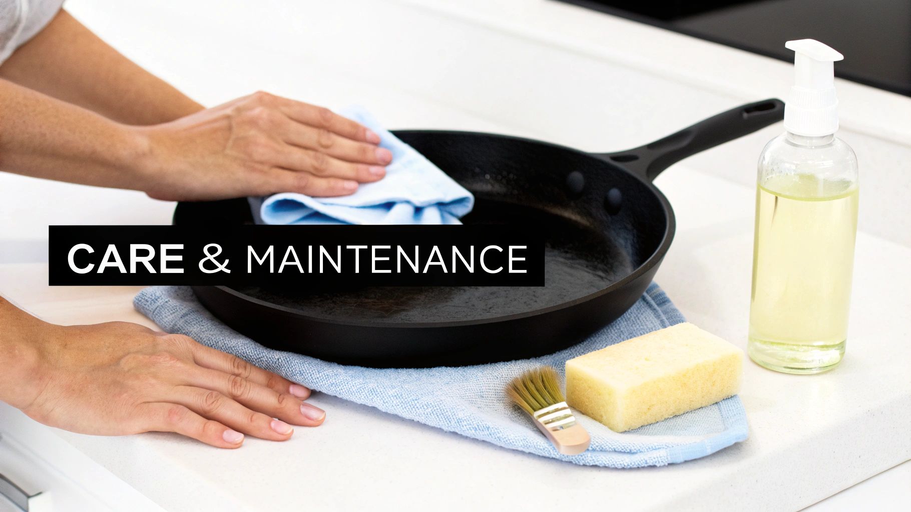 Hands cleaning a black cast iron pan with a cloth, sponge, and oil on a kitchen counter.