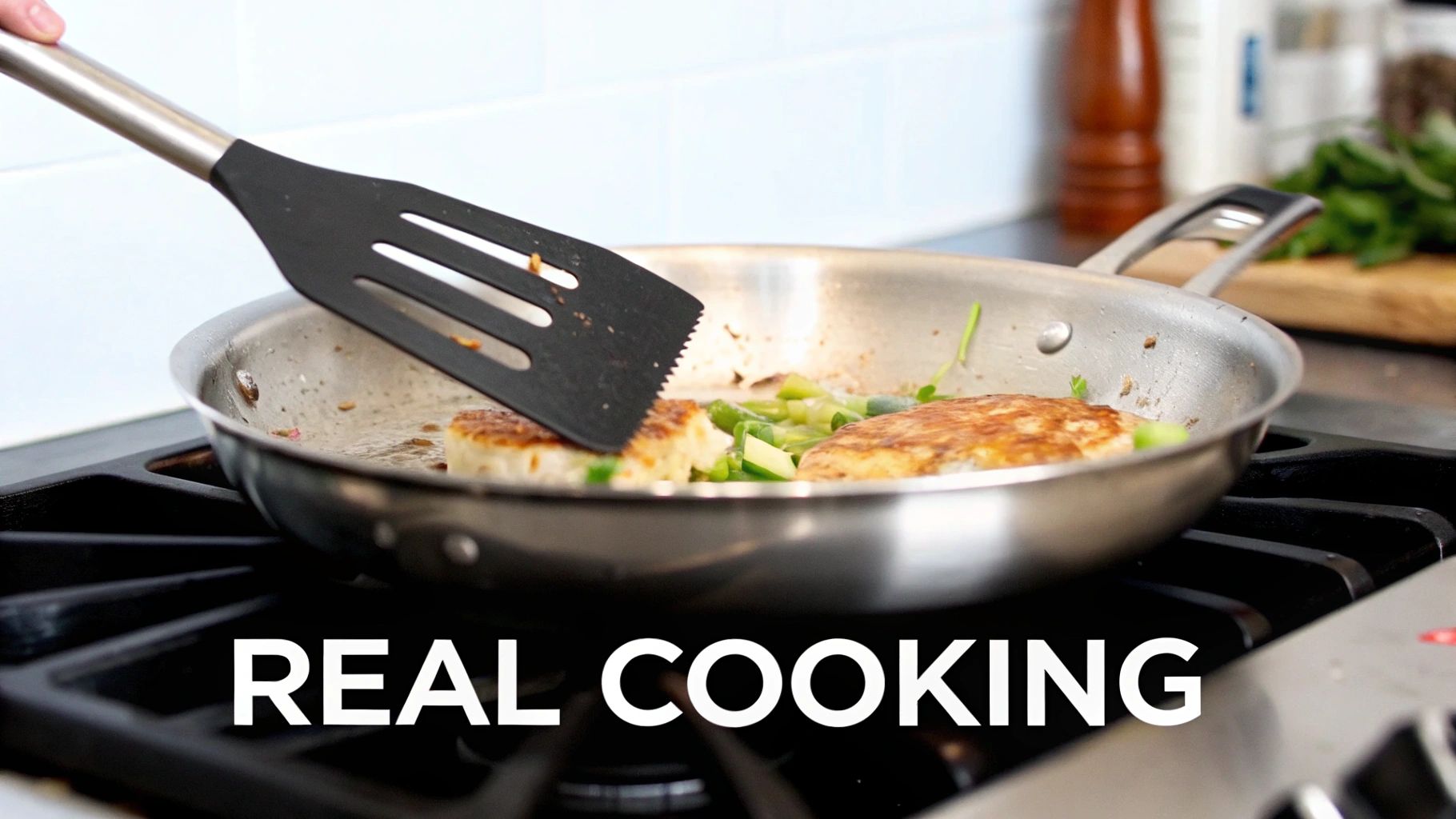 A close-up of a person using a black spatula to flip food in a stainless steel pan on a stove.