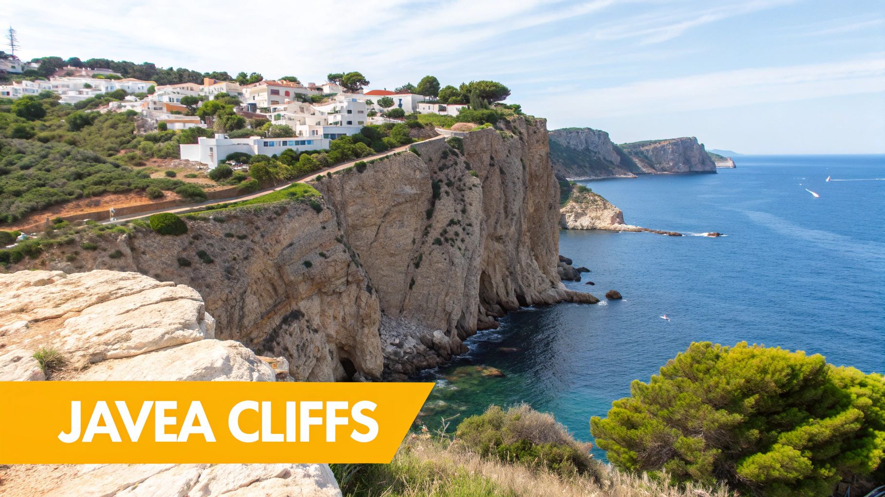 Panoramic view of Javea's white cliffside houses overlooking the deep blue Mediterranean Sea with boats.